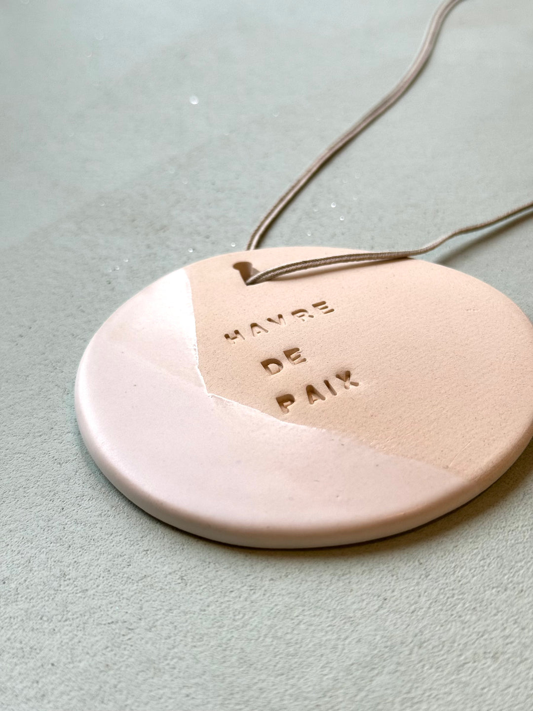 le médaillon en céramique décoratif et à parfumer gravé du mantra havre de paix signé Domaine Singulier et façonné par une artiste céramiste française