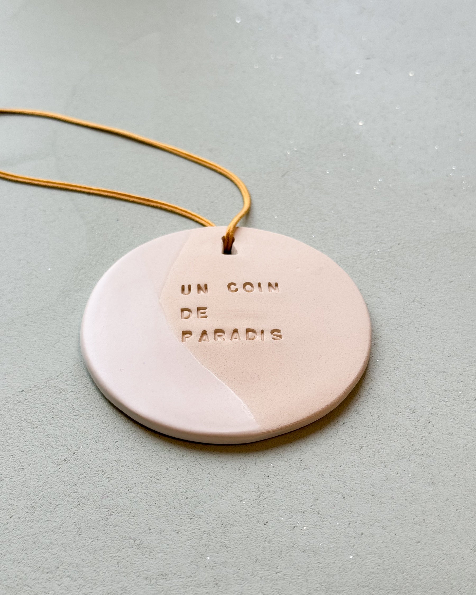 le médaillon Domaine Singulier en céramique pour décorer et  à parfumer, gravé du mantra un coin de paradis