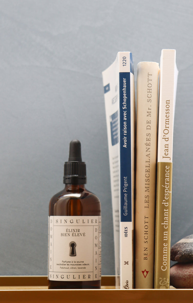 L' Elixir Bien Elevé de Domaine Singulier ici posé à côté de livres inspirants pour faire une pause agréable aux toilettes et dans la salle de bain